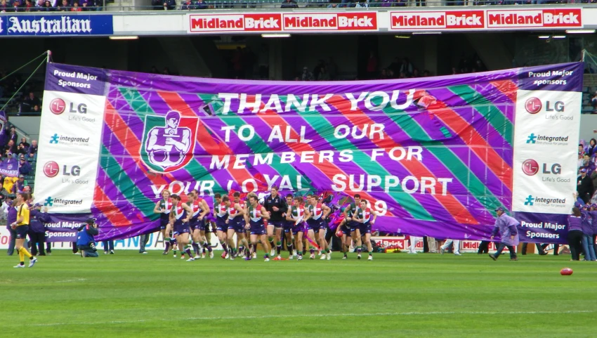 many people are lined up in front of a large sign on a field