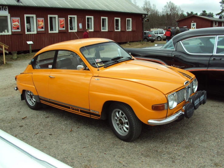 an orange car sitting next to another old car