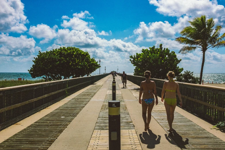 two women walk down a bridge with a view of the water