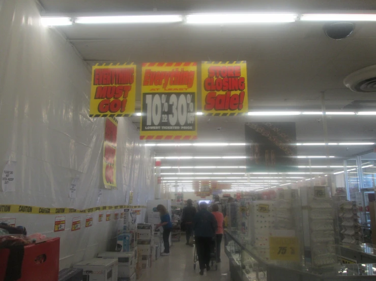 people are walking through a store under the lights