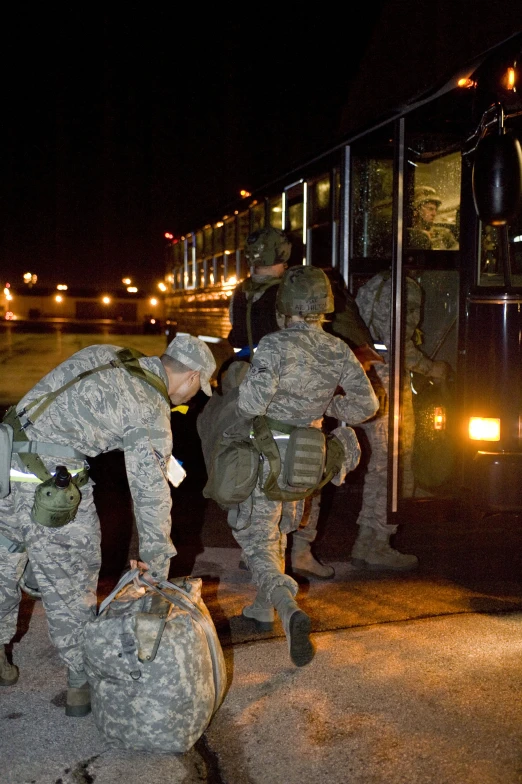 four military men loading a big white bus