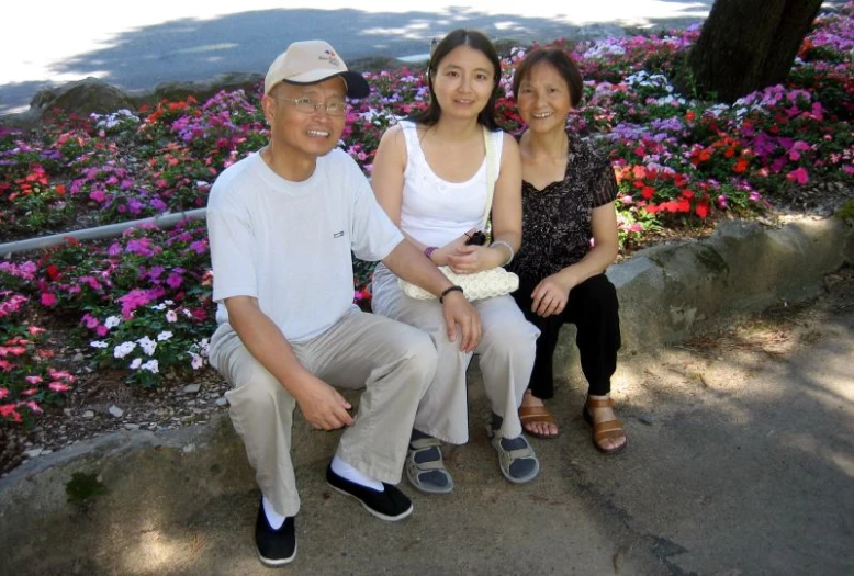 a family sitting on the steps in front of flowers