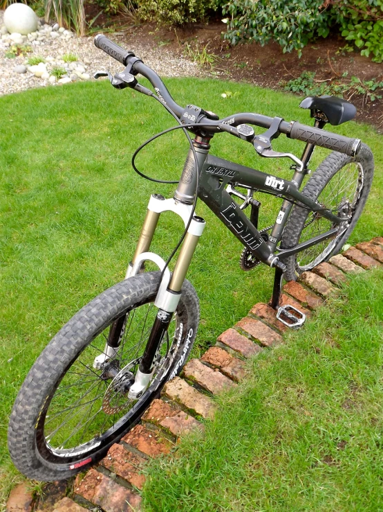 the bike is propped against the brick wall outside