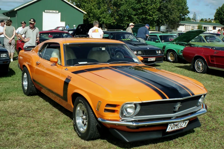 an orange muscle car with a black stripe on the front and black stripe on the side