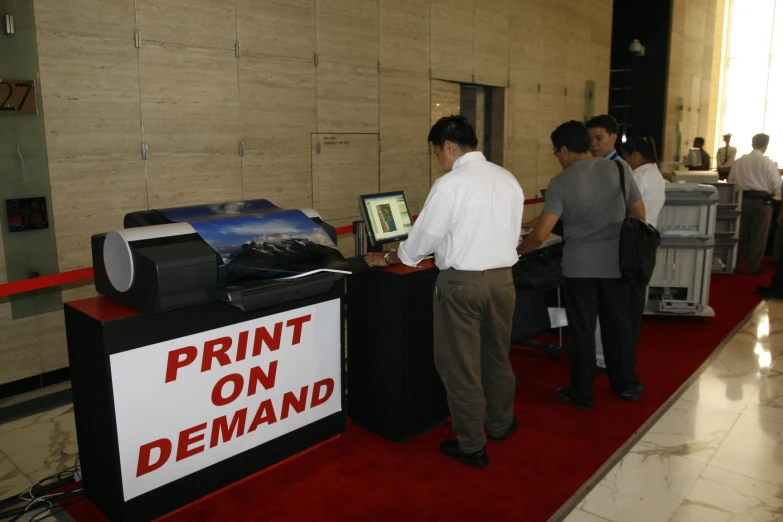 two men talking at a printer on demand booth