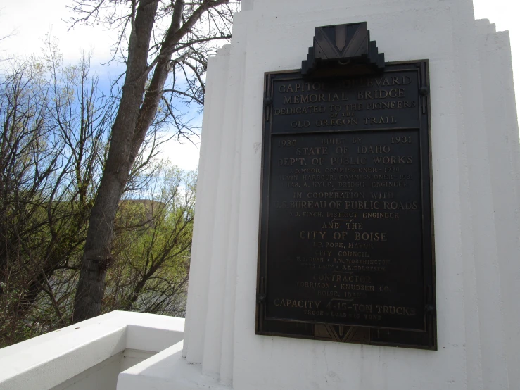 the memorial plaque on the wall is beside a tree