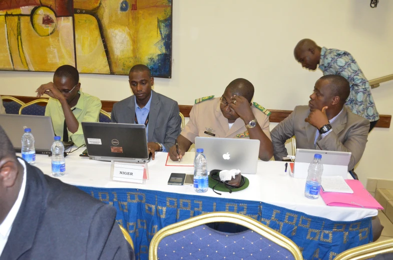 people sit at a conference table while they look at a laptop