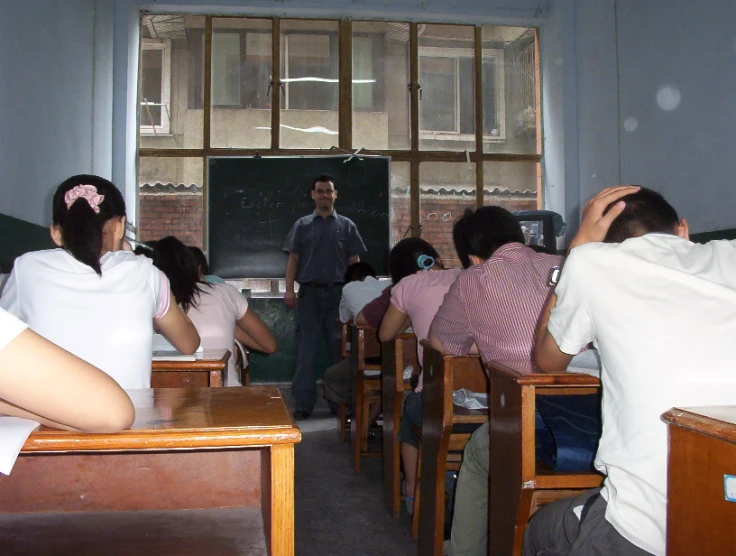 several people in a classroom are sitting at desks