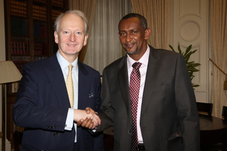 a man holding another man's hand smiling and shaking hands