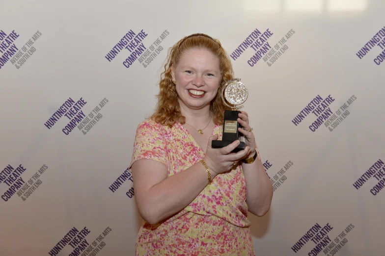 a lady holding up an award in her hands