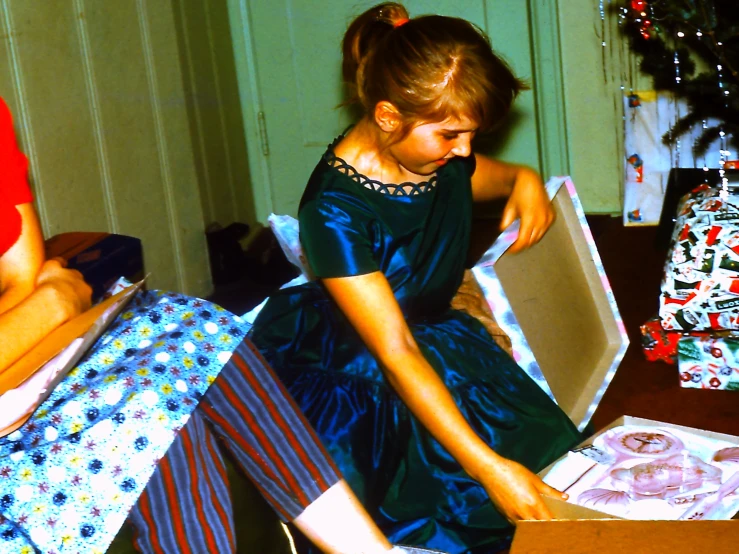 a little girl opening a box that has a large amount of gifts