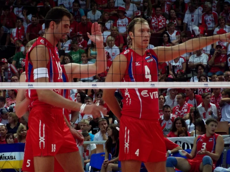 two volleyball players standing in front of an audience during a match