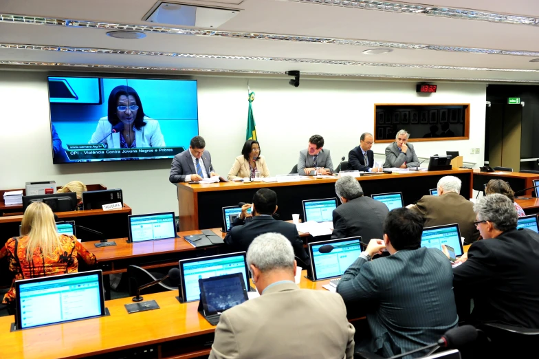 a group of people sitting at laptops in front of a screen