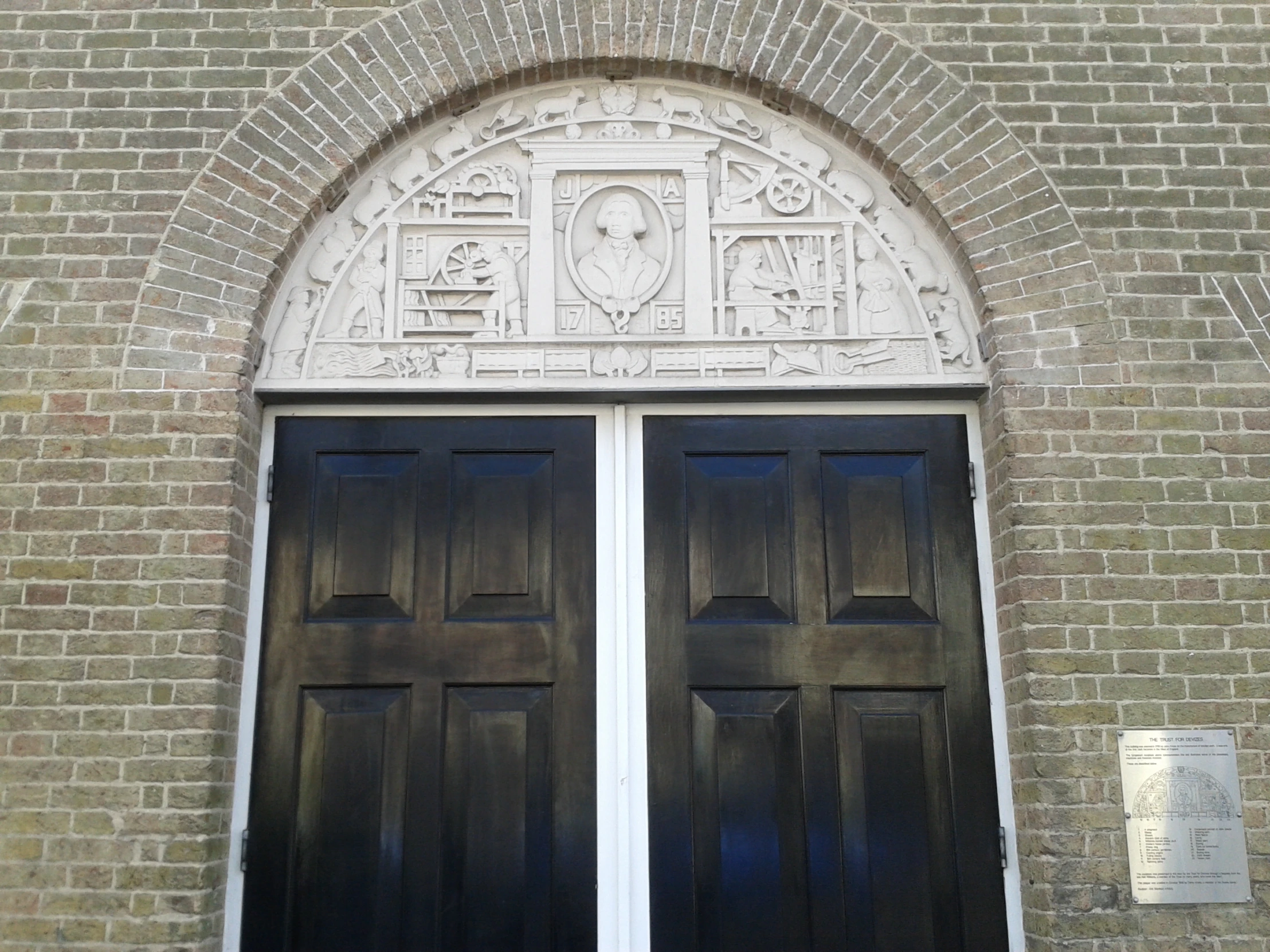 large, dark brown doors are flanked by a brick archway