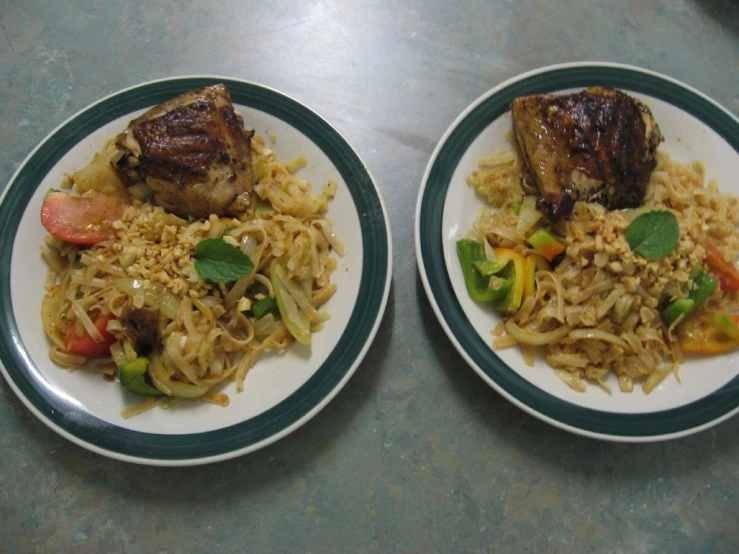 two plates containing rice, meat and vegetables are sitting on a table