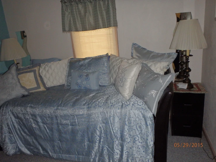 the blue bed is covered with many decorative pillows