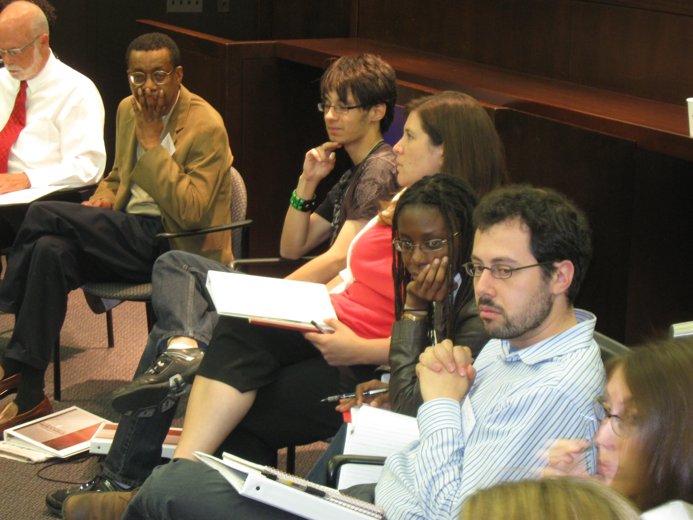 a group of people sitting in a room with a lady on her phone