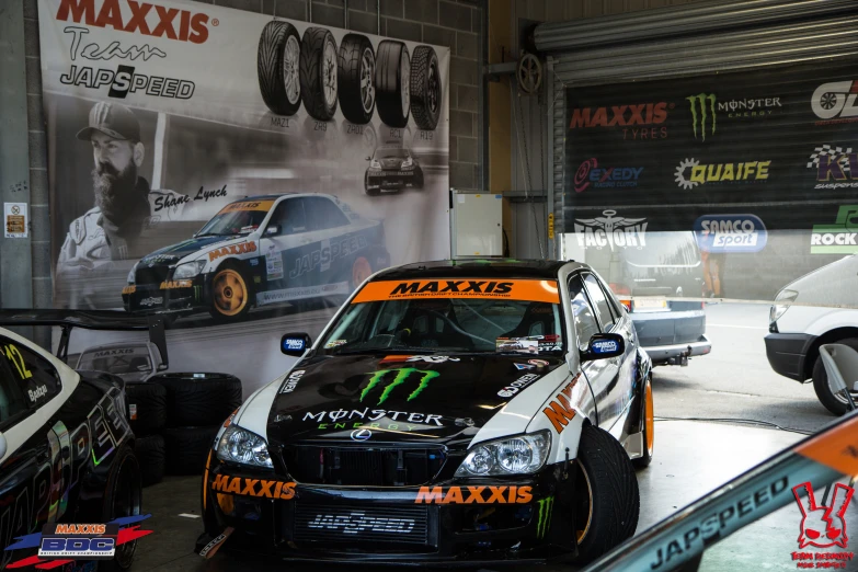 several cars parked inside of a garage with a huge wall of advertising