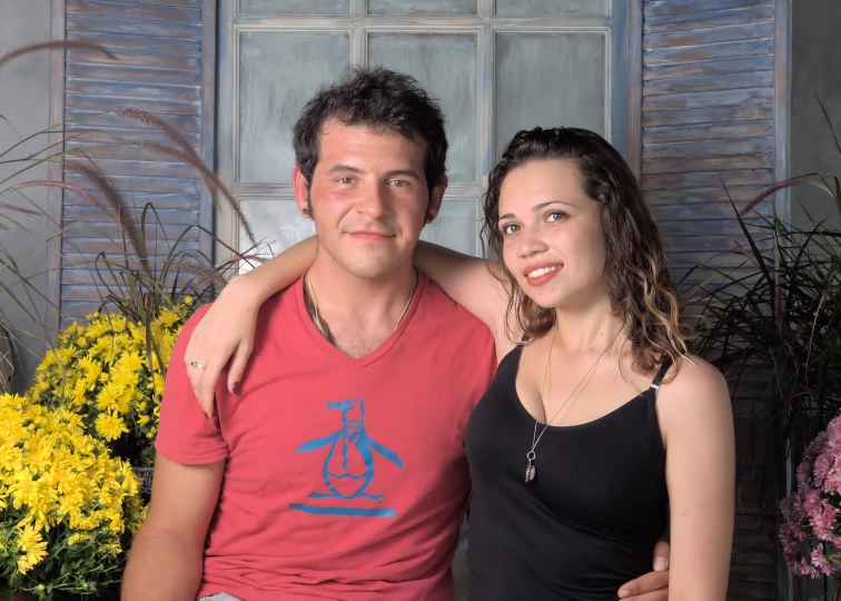 a man and woman are posing together in front of flowers