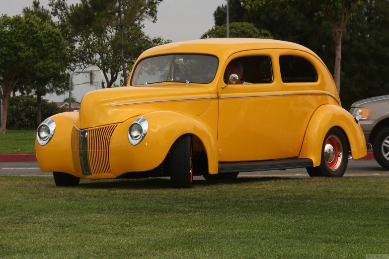 an antique yellow car sits in a parking space