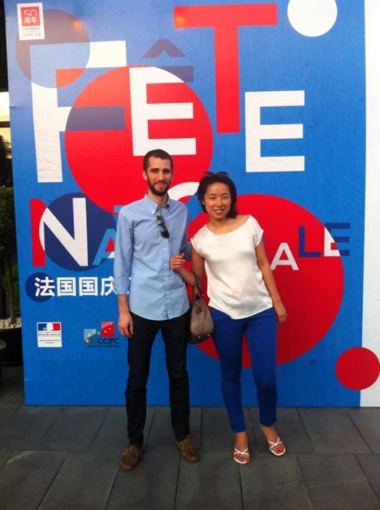 an asian couple posing in front of a wall