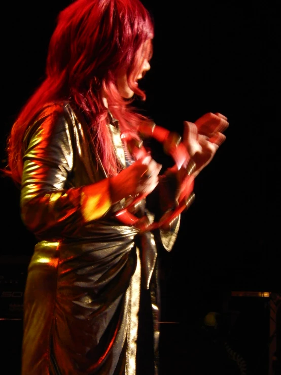 a woman on stage performing in an orange and silver outfit