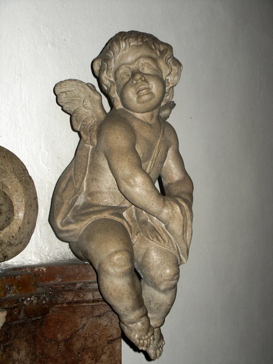 a statue of an angel sitting on a shelf