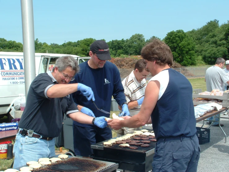 several men are cooking outdoors at an event