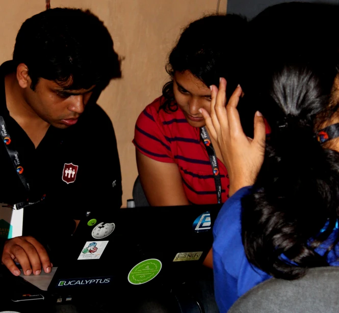 three people are around a black laptop