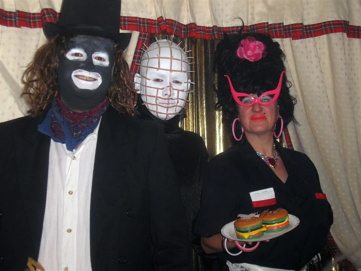 a woman standing between two men in fancy makeup