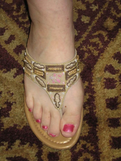 a woman's foot with beaded sandals on it