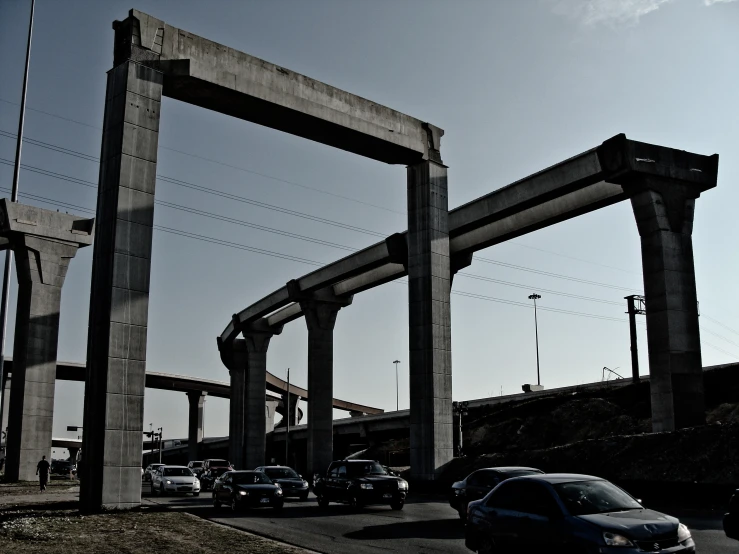 cars driving under multiple concrete structures that have been made to look like columns