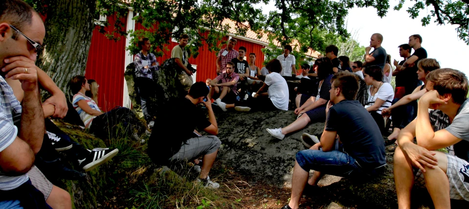 a group of people that are sitting in front of some tree