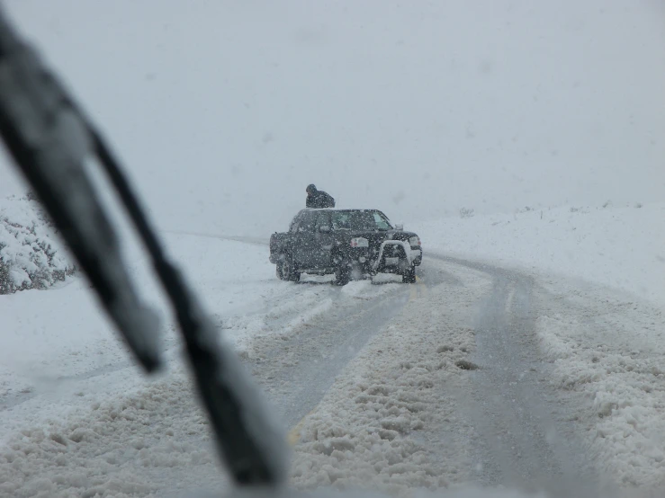 a man is standing in the car on a snowy road