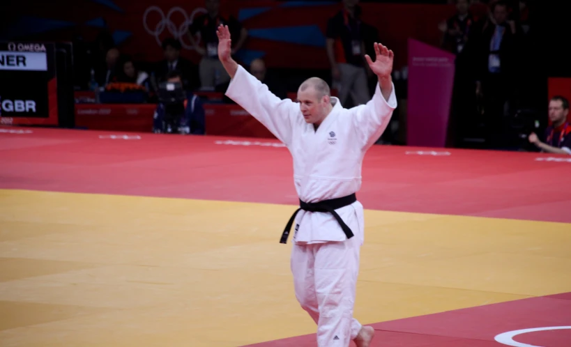 man in white kimono with arms up on court