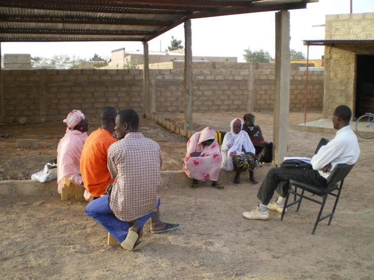 a group of people sitting on a sandy surface