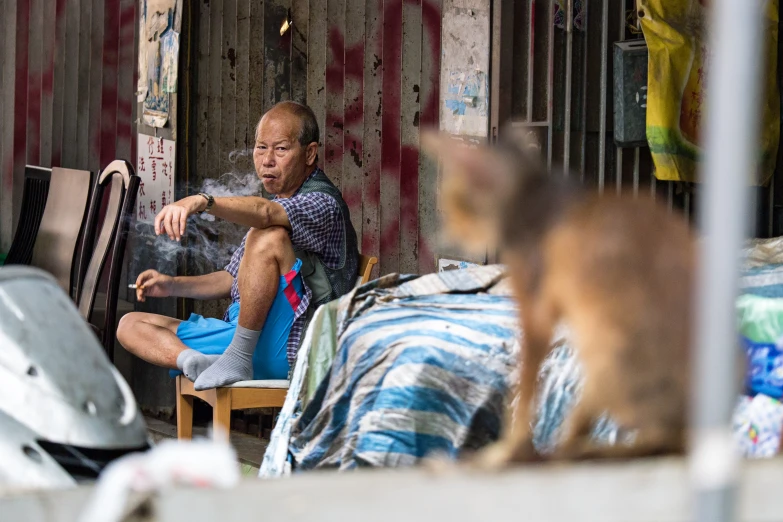 a man sits on a chair outside a small wooden cabin