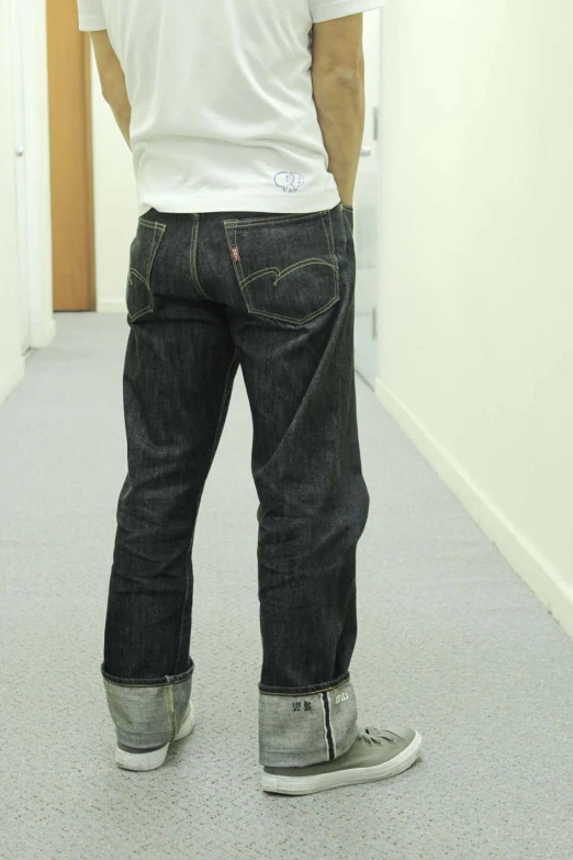 a man in jeans standing on a hallway floor looking back