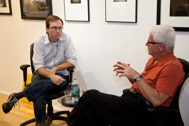 two men sitting next to each other in chairs