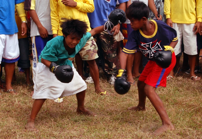 a little boy is holding two boxing gloves on his back