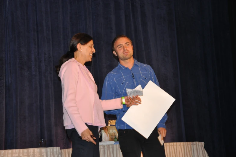 a man is shaking the hand of another person in front of a curtain