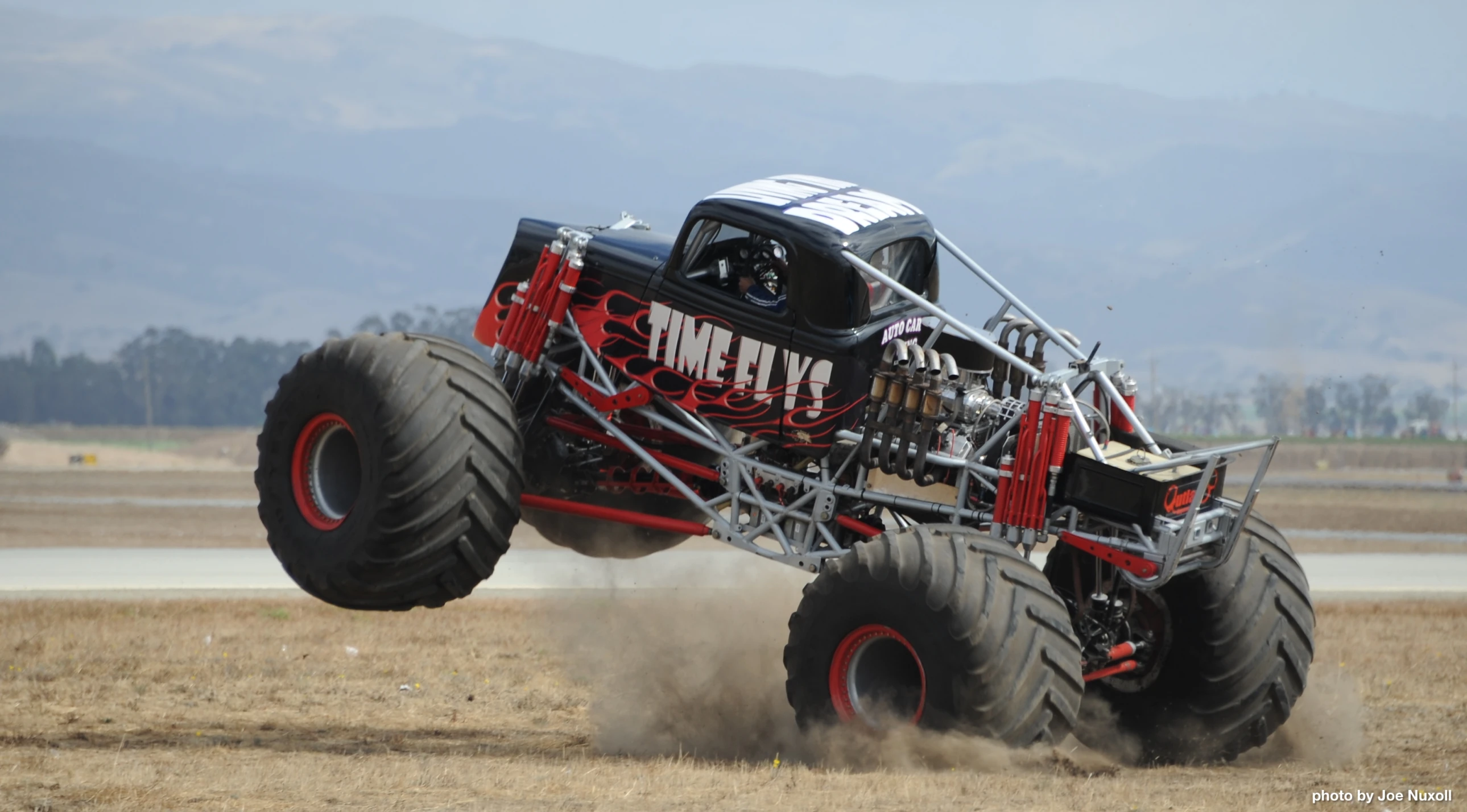 an monster truck drives through dirt while hitting it's tires