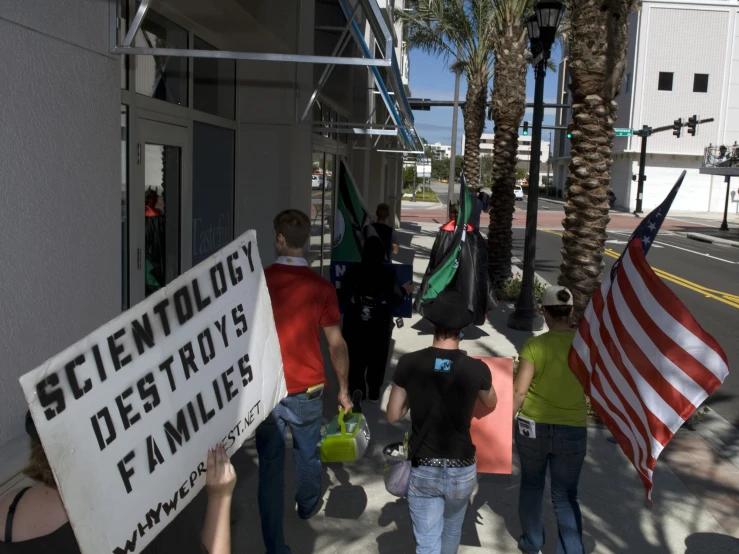 a group of people walking down a sidewalk carrying flags and signs