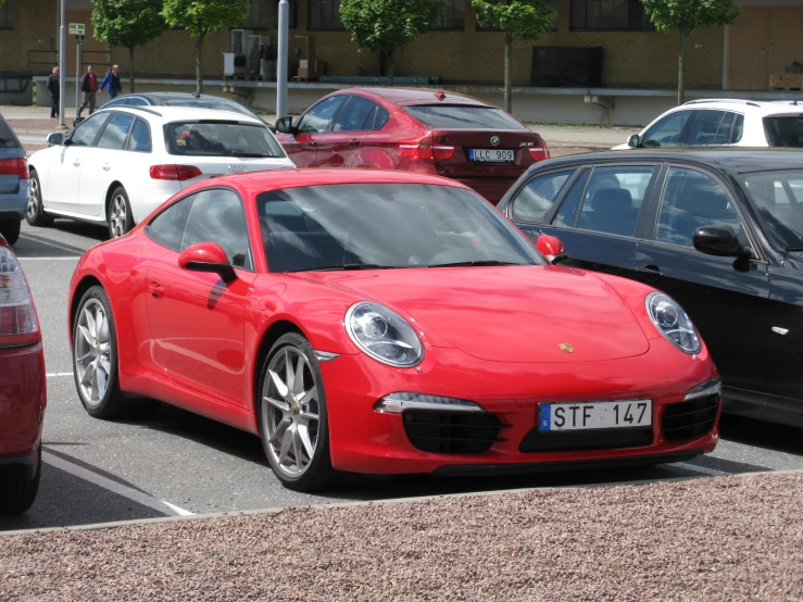a red porsche on a city street with several other cars