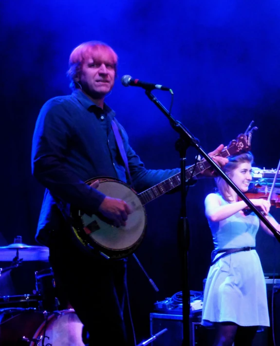 a man holding a guitar standing next to a woman