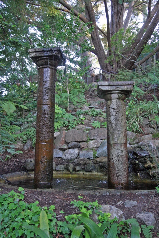 a few stone columns with a water feature