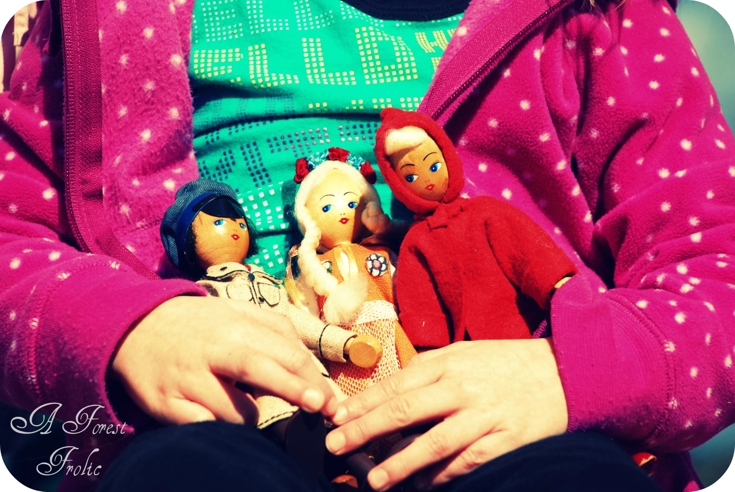 a  in a pink sweater holds five dolls