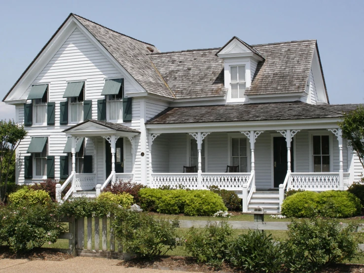 an old victorian white house with large porch and white railing
