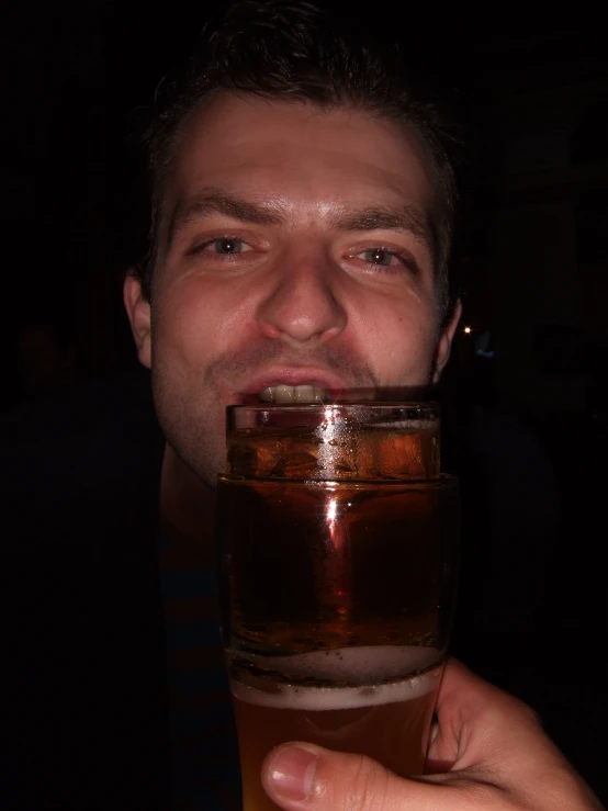 a man holding up a beer mug with liquid inside