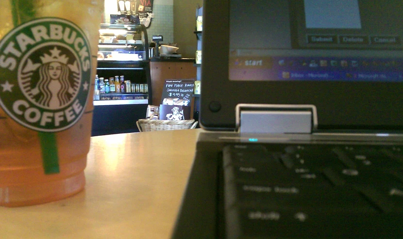 starbucks drink next to a laptop computer on the table